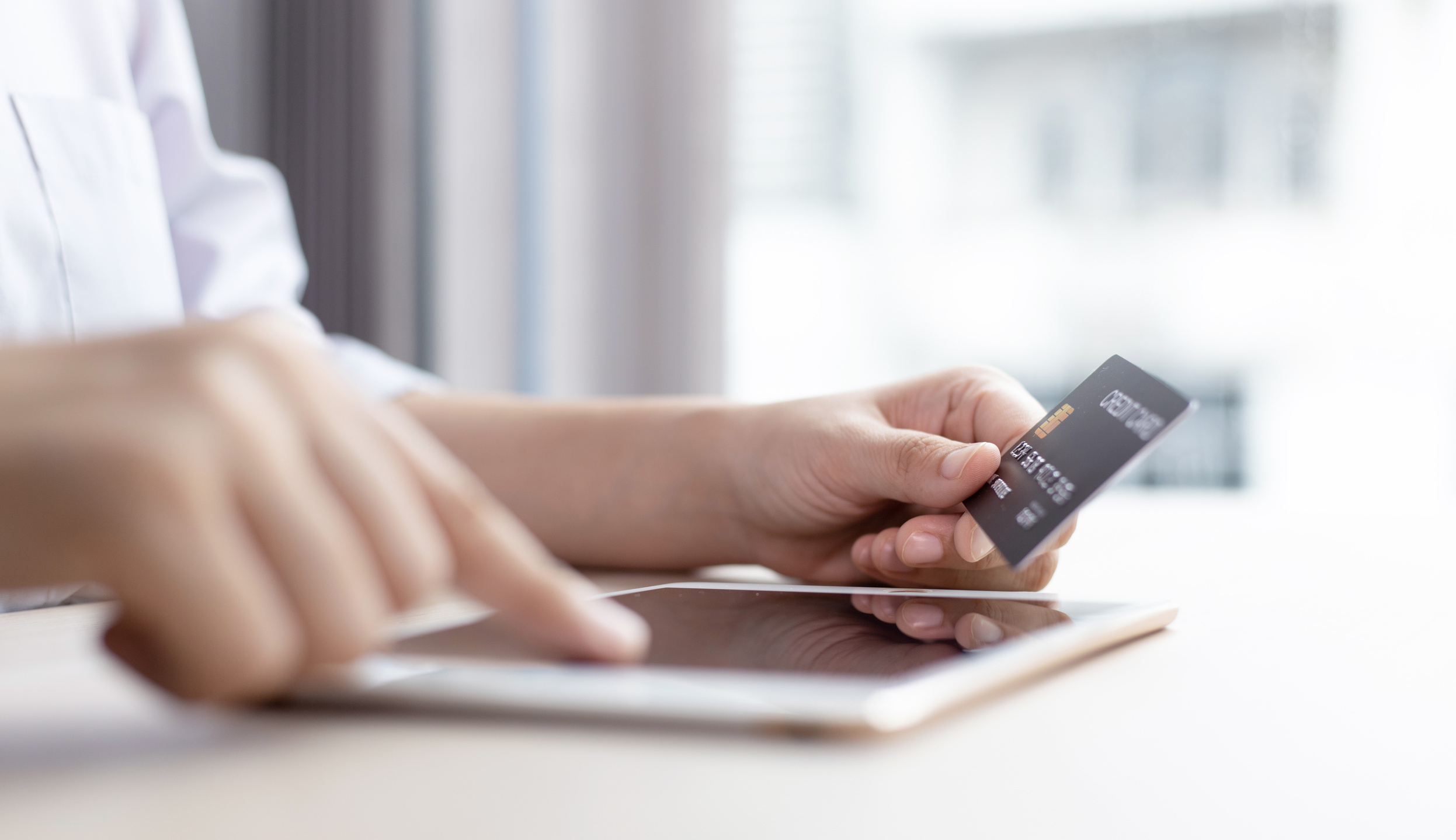 Woman's Hand Using Tablet to Pay Online with Credit Card